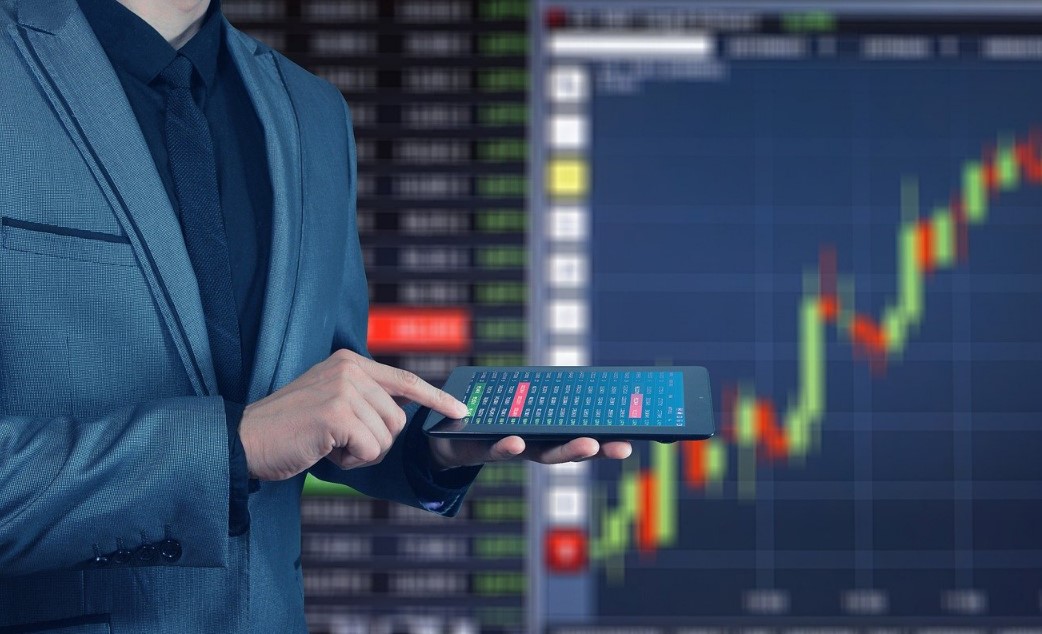 Trader holding phone with trade stock analytics in the background